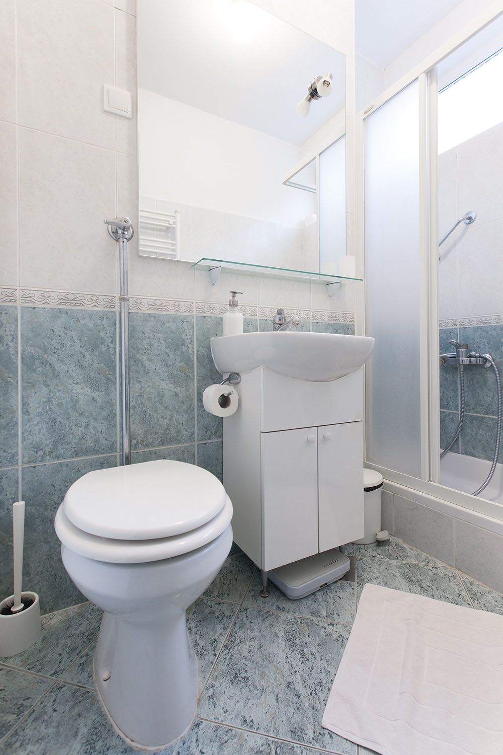 Bathroom with shower, washing machine, sink and toilet.