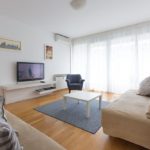 Living room with two sofa beds, armchair, TV, entrance to the terrace and big windows.