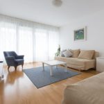 Living room with two sofa beds, armchair, TV, entrance to the terrace and big windows.