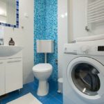 Bathroom with bath tub and shower, sink, toilet, and washing machine.