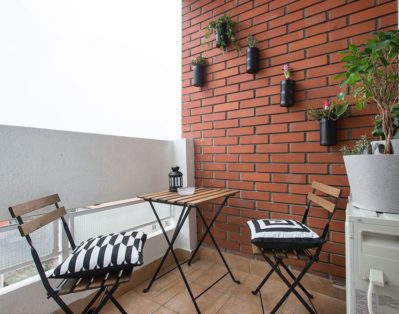 Terrace with table and chairs and flowers on the red brick wall.