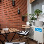 Terrace with table and chairs and flowers on the red brick wall.