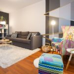 Living room with double sofa bed, armchair and shelf with books and decoration.