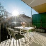 Sunny terrace with flowers and table with 4 chairs.