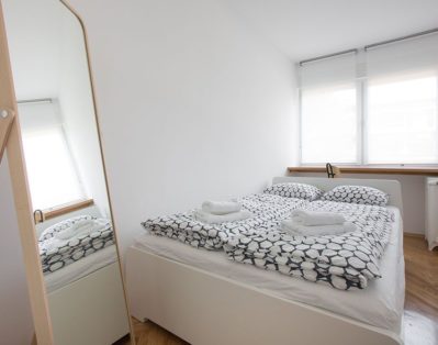 Bedroom with double bed, working table and big mirror.