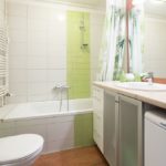 Bathroom with bath tub and shower, toilet, sink and washing machine.